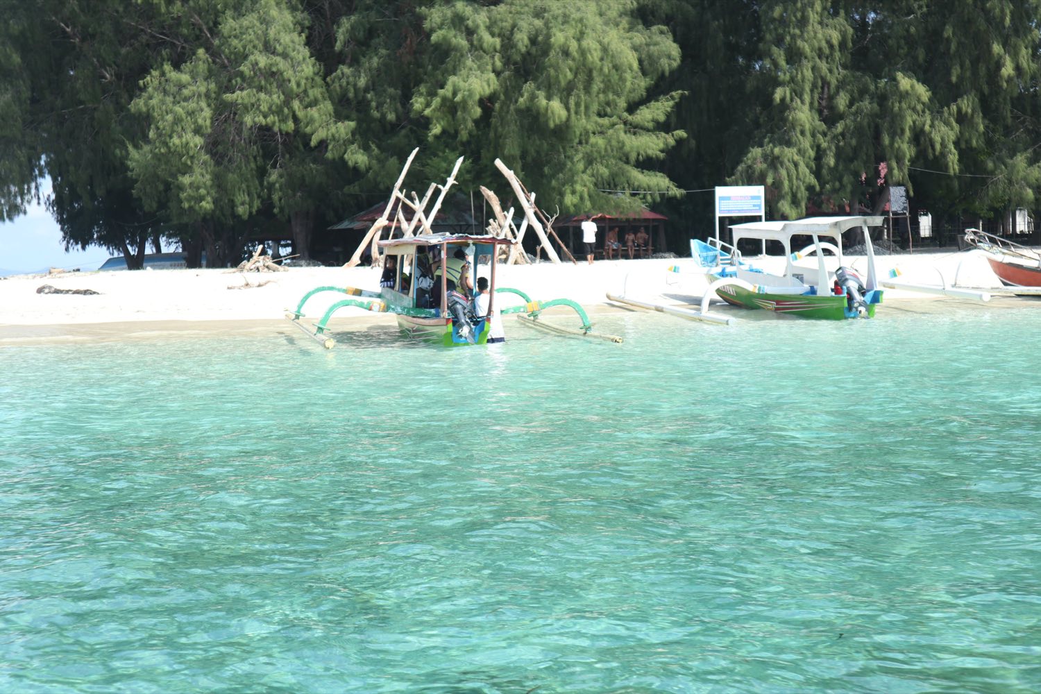 Small white-sand Gili island ringed by clear turquoise water and traditional outrigger boats off south-west Lombok